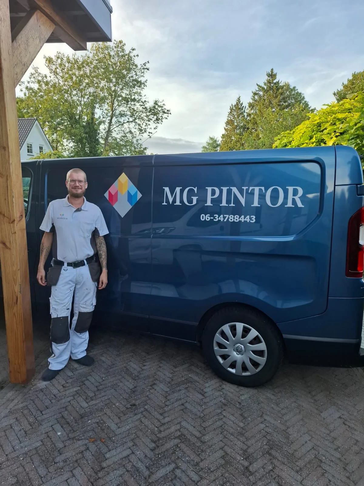 De eigenaar van MG Pintor voor de bedrijfsbus met het logo en telefoonnummer