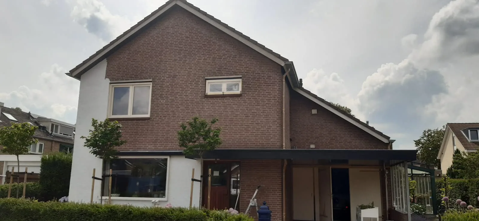 Vrijstaande woning vóór het schilderwerk: donkere baksteengevel met houten kozijnen
