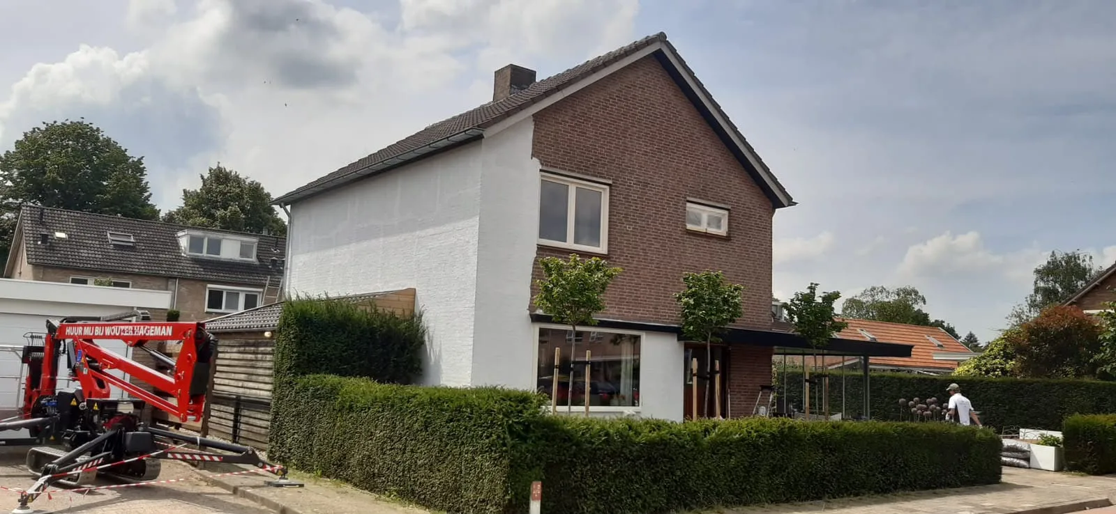Dezelfde woning halverwege het werk, met hoogwerker; de topgevel is al wit